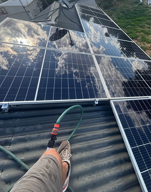Solar panel cleaning technician safely cleaning rooftop panels in Dubbo